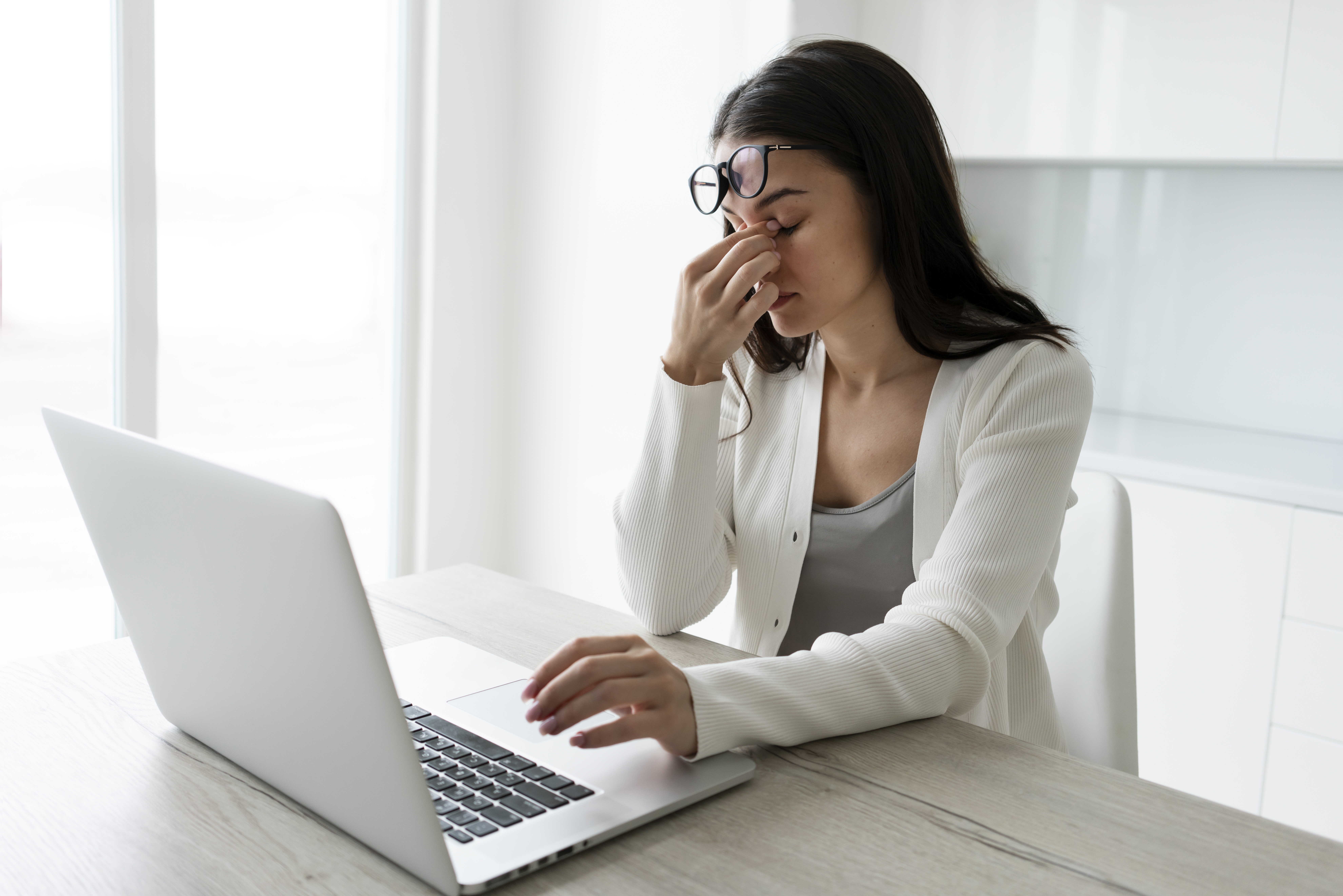 Woman rubbing her eyes in fatigue while working on a laptop